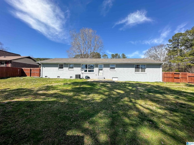 back of property featuring crawl space, a lawn, brick siding, and fence