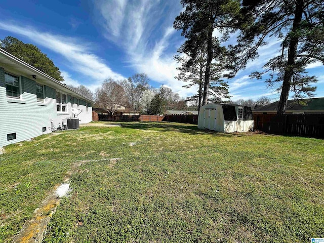 view of yard featuring an outbuilding, cooling unit, a storage unit, and a fenced backyard