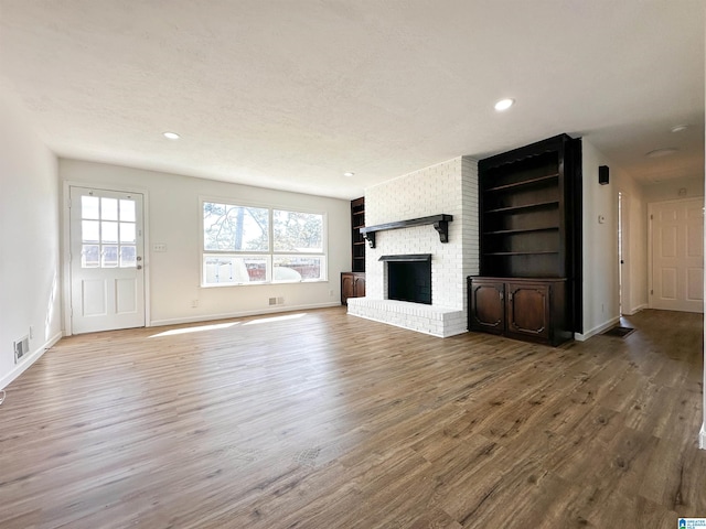 unfurnished living room with recessed lighting, a fireplace, baseboards, and wood finished floors