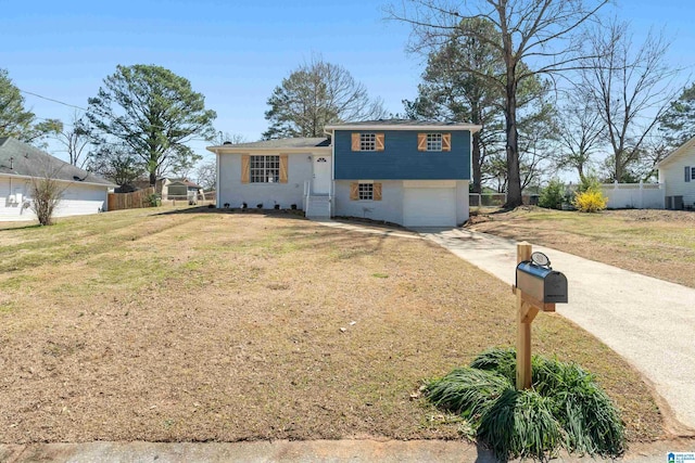 split level home with a garage, a front yard, concrete driveway, and fence