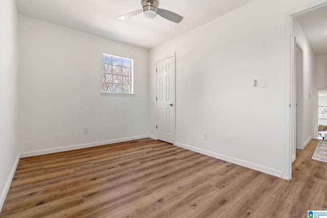 empty room with a ceiling fan, baseboards, and wood finished floors