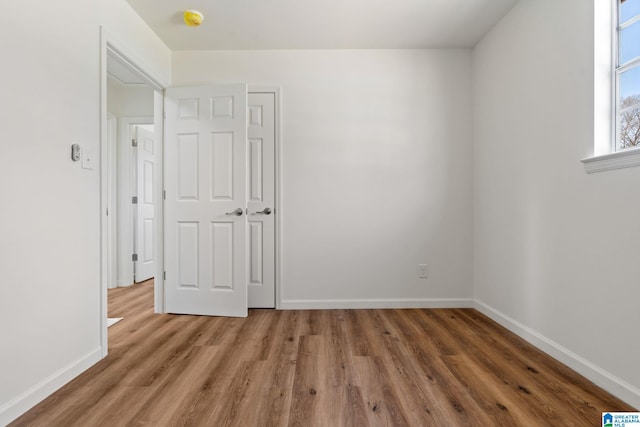 spare room with baseboards and wood finished floors