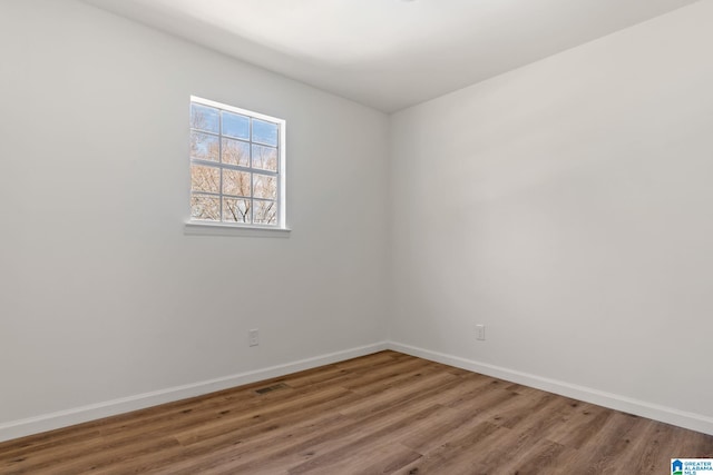 spare room with baseboards and wood finished floors