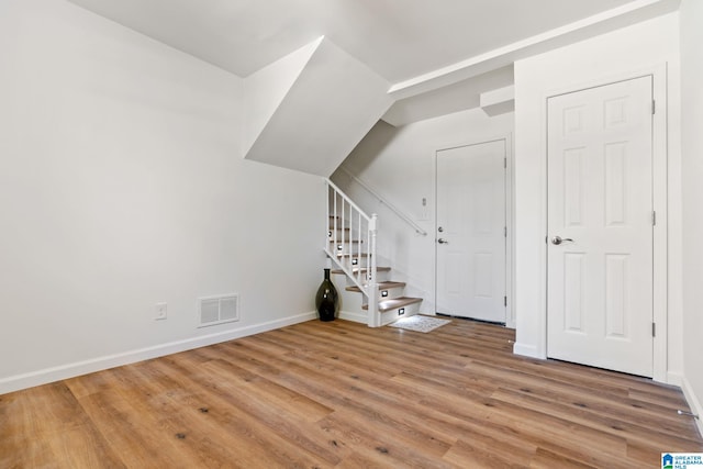 interior space featuring baseboards, visible vents, stairway, and light wood finished floors