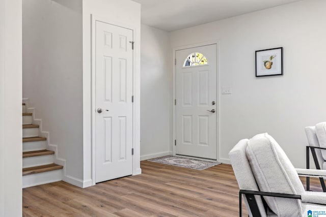 foyer entrance featuring baseboards, stairway, and wood finished floors