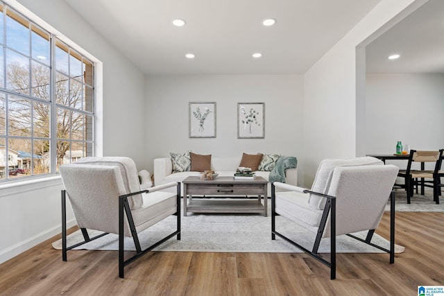 living area with baseboards, wood finished floors, and recessed lighting