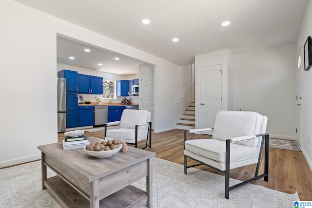 living room featuring light wood-style flooring, recessed lighting, stairway, and baseboards