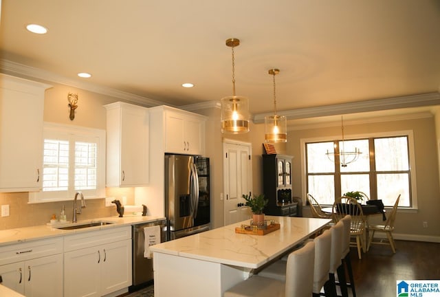 kitchen featuring a center island, crown molding, white cabinets, stainless steel appliances, and a sink