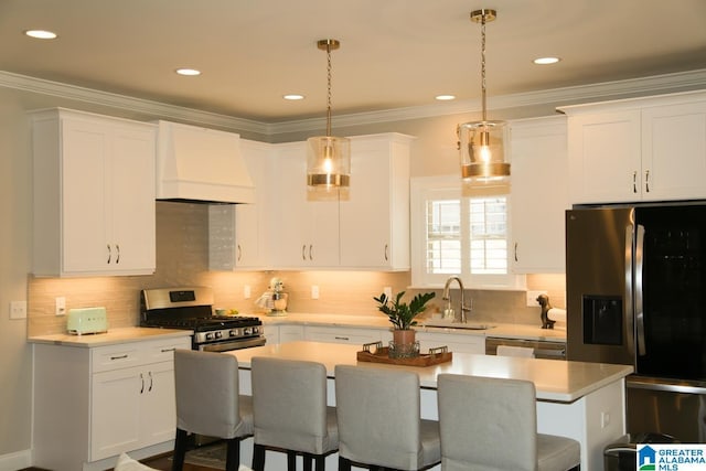 kitchen featuring premium range hood, a sink, stainless steel appliances, a breakfast bar area, and crown molding