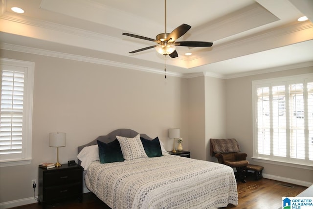 bedroom featuring visible vents, crown molding, baseboards, a tray ceiling, and dark wood-style floors