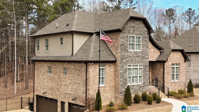 view of front of property featuring fence, stone siding, and roof with shingles