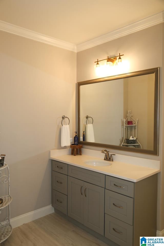 bathroom featuring vanity, crown molding, baseboards, and wood finished floors