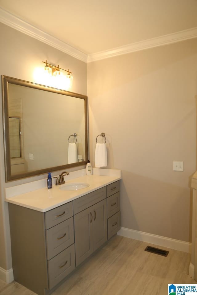 bathroom featuring visible vents, wood finished floors, ornamental molding, and vanity