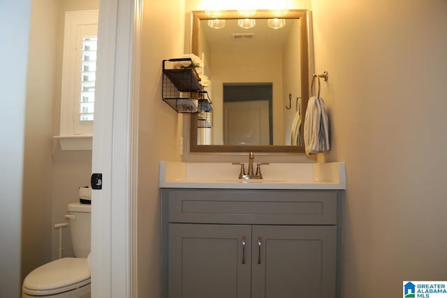 bathroom featuring visible vents, toilet, and vanity