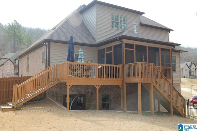 back of property featuring stairs, a deck, a sunroom, and a shingled roof