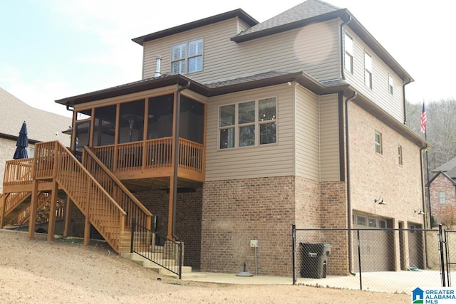 back of property featuring brick siding, fence, stairs, and a sunroom