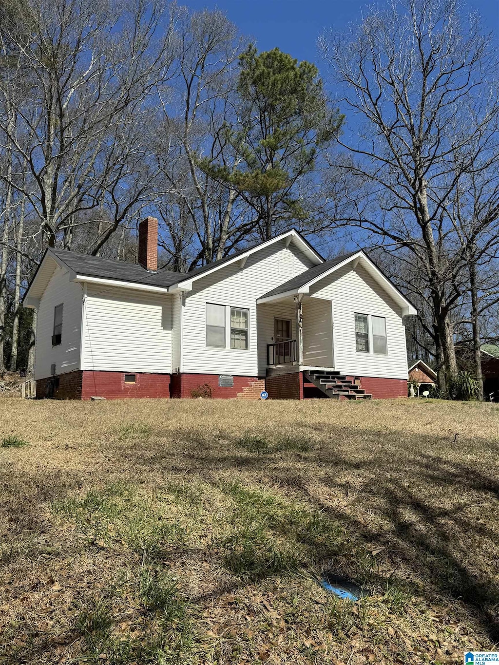 view of front of house featuring crawl space, covered porch, a chimney, and a front yard