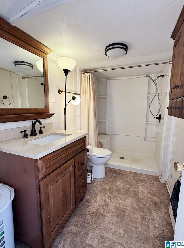 bathroom featuring toilet, a shower stall, and vanity