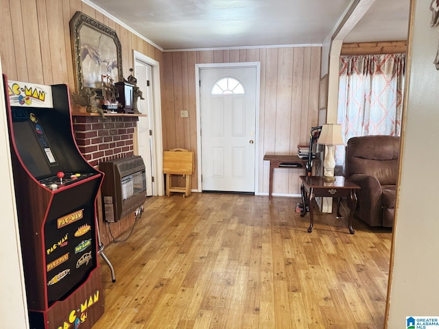 entrance foyer with ornamental molding, a wood stove, hardwood / wood-style floors, and heating unit