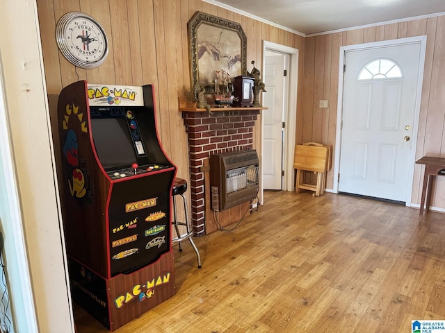 entrance foyer featuring hardwood / wood-style flooring, wooden walls, ornamental molding, a brick fireplace, and heating unit