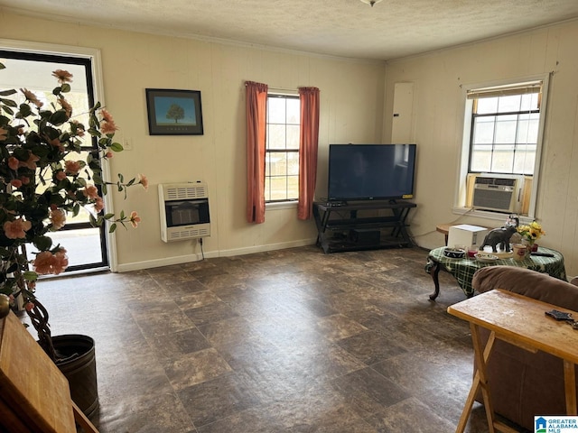 living area with heating unit, stone finish floor, a textured ceiling, cooling unit, and baseboards