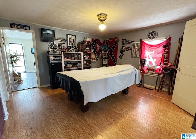 bedroom with pool table, ornamental molding, light wood-style flooring, and baseboards