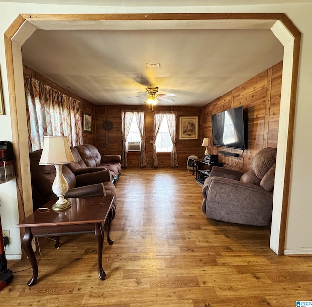 living area featuring ceiling fan, wood walls, cooling unit, and wood finished floors