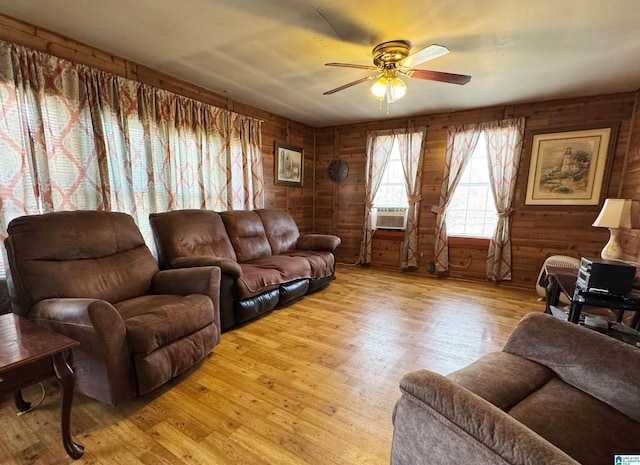 living room with light wood-style floors, cooling unit, a ceiling fan, and wood walls