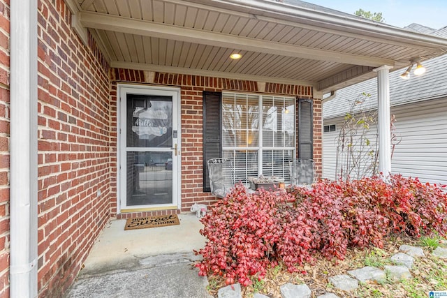 doorway to property featuring brick siding and a porch