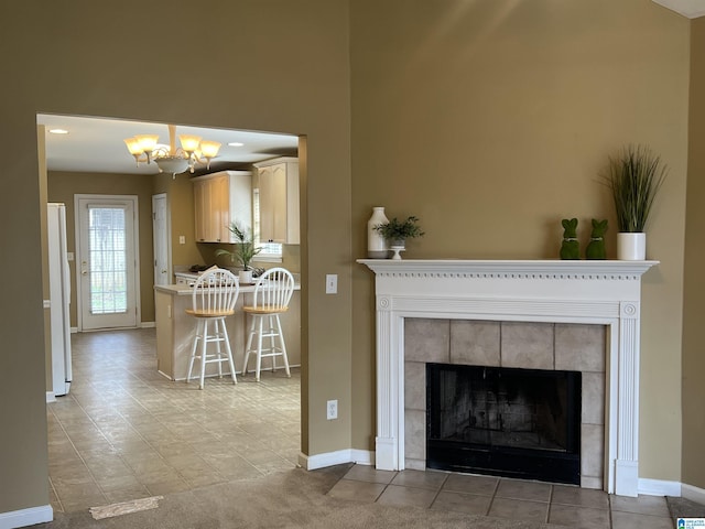 living room with a tiled fireplace, an inviting chandelier, and baseboards