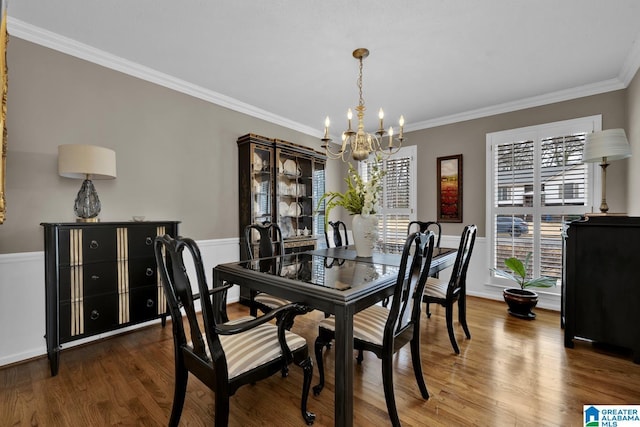 dining area with crown molding, wood finished floors, and a notable chandelier