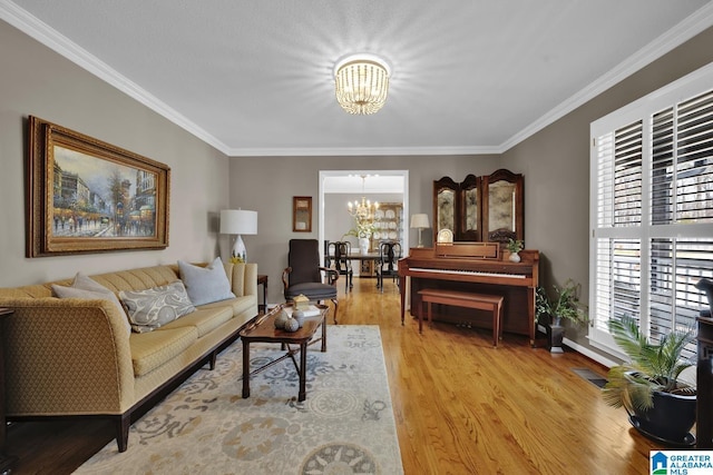 living area with light wood-type flooring, a healthy amount of sunlight, a chandelier, and ornamental molding