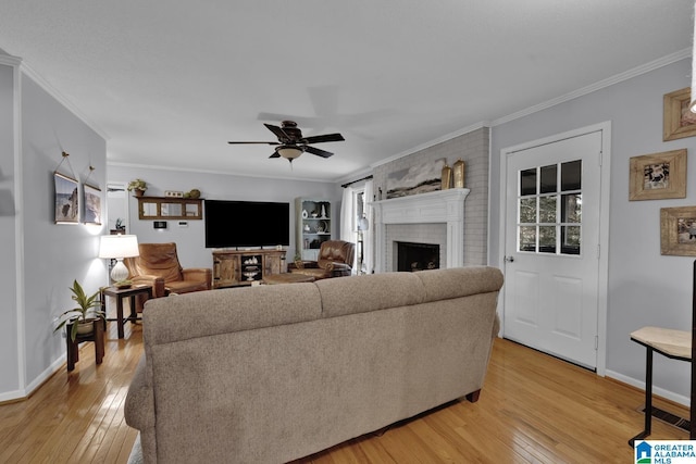 living room featuring a healthy amount of sunlight, a brick fireplace, light wood-style flooring, and crown molding