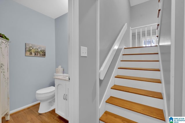 staircase featuring baseboards and wood finished floors