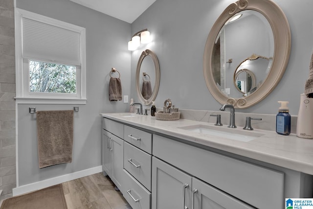 full bath with double vanity, baseboards, and a sink