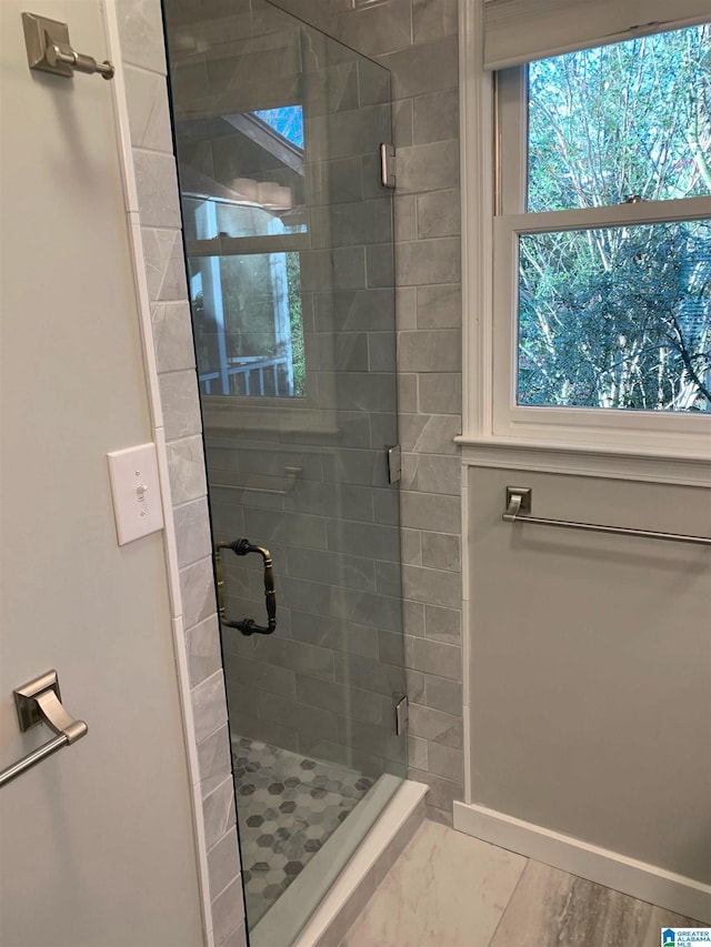 full bathroom with a shower stall and baseboards