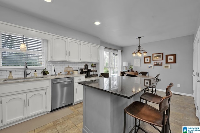 kitchen with decorative backsplash, a breakfast bar, stainless steel dishwasher, white cabinetry, and a sink