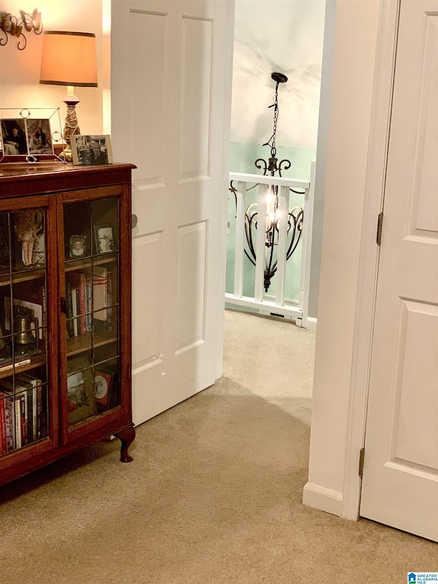 hallway with an inviting chandelier, carpet, and baseboards