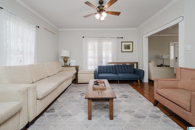 living area featuring crown molding, light wood-style flooring, and a ceiling fan