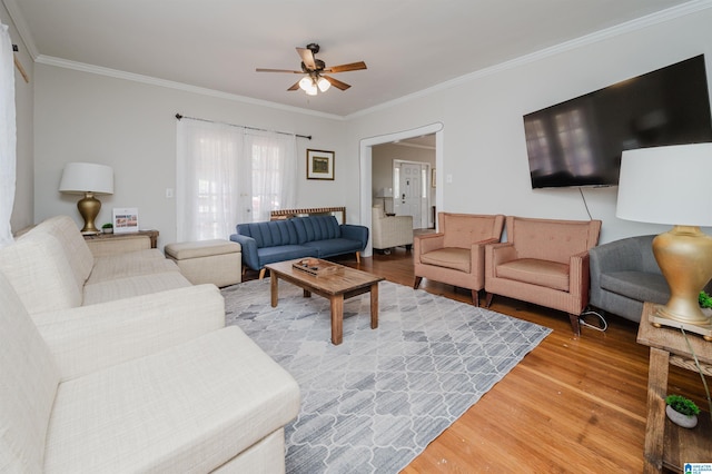 living area featuring wood finished floors, a ceiling fan, and ornamental molding