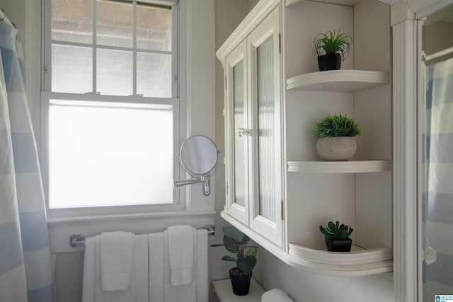 bathroom featuring a shower with shower curtain, radiator, and a healthy amount of sunlight