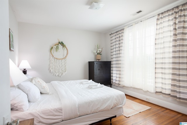 bedroom with wood finished floors, visible vents, and baseboards