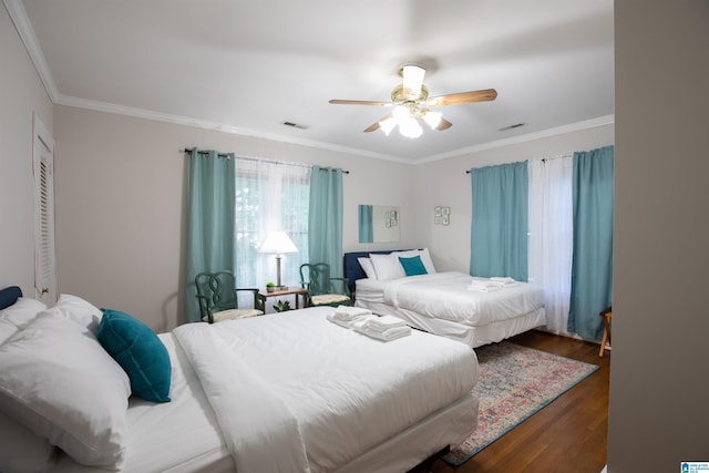 bedroom with visible vents, crown molding, ceiling fan, and wood finished floors