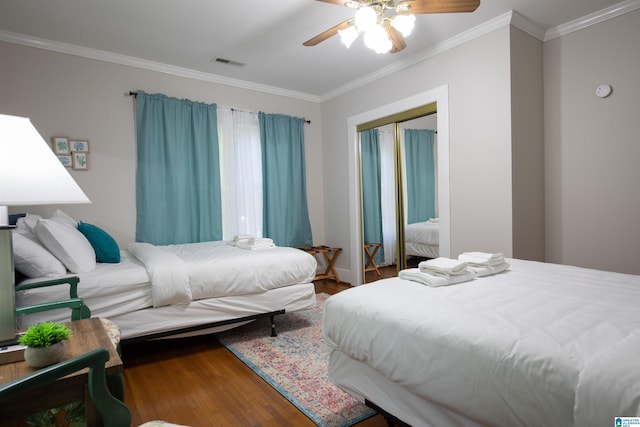 bedroom featuring wood finished floors, visible vents, ceiling fan, ornamental molding, and a closet