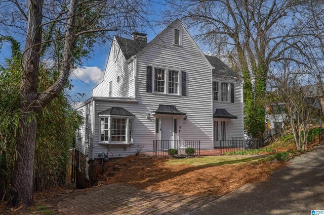 view of front of property with roof with shingles and a chimney