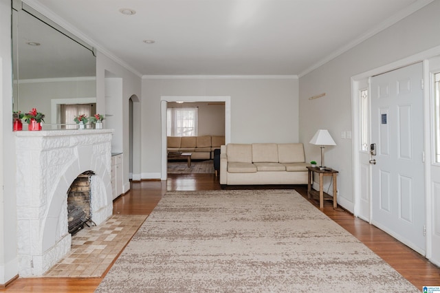 living room featuring arched walkways, crown molding, and wood finished floors