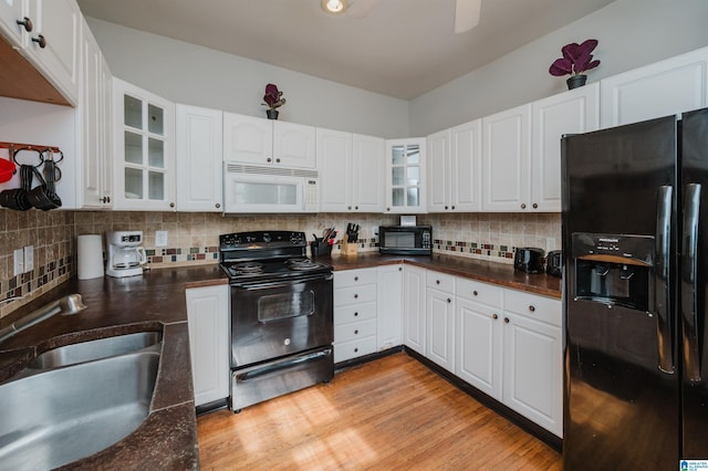 kitchen with dark countertops, decorative backsplash, black appliances, and a sink