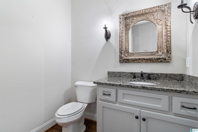 bathroom featuring toilet, baseboards, wood finished floors, and vanity