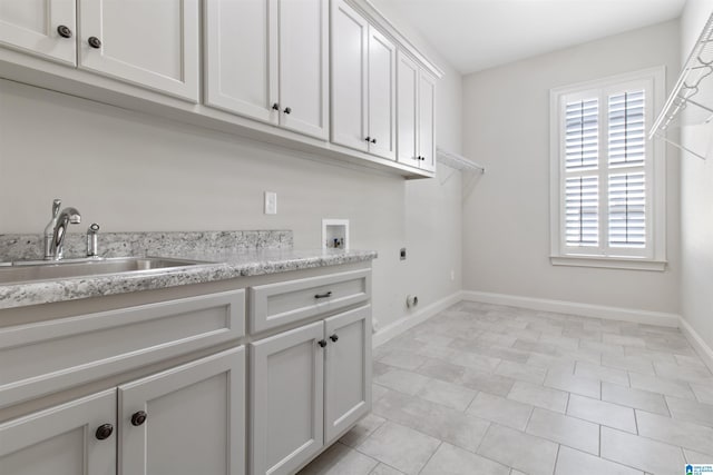 clothes washing area with cabinet space, baseboards, hookup for a washing machine, electric dryer hookup, and a sink