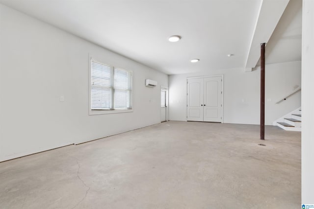 interior space featuring concrete flooring, a wall unit AC, and stairs